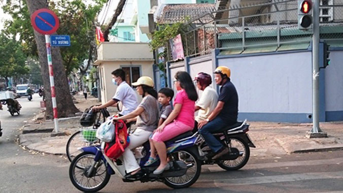 Nhiều phụ huynh học sinh chưa chấp hành cho con em mình đội mũ bảo hiểm khi ra đường.