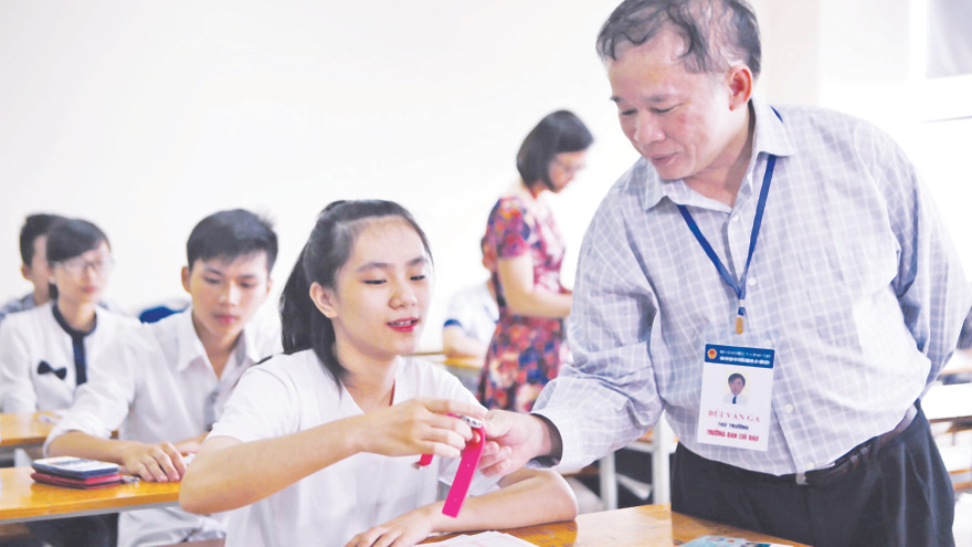 Thứ trưởng Bùi Văn Ga kiểm tra đồng hồ của một thí sinh ĐH Ngoại thương, sau đó chúc học sinh này thi tốt. Ảnh: Như Ý 