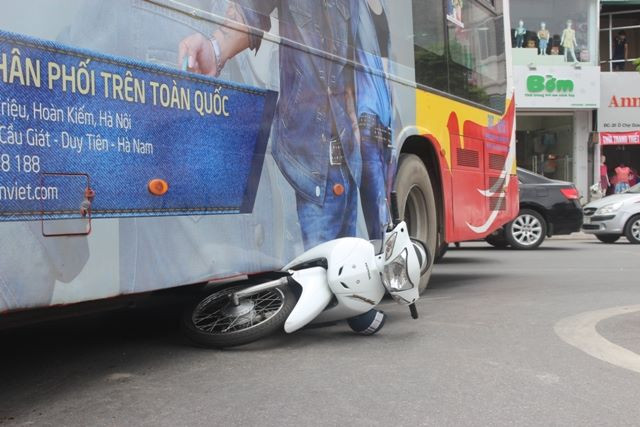 Chiếc xe máy mắc kẹt dưới gầm xe buýt.