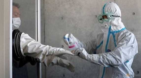 Một nhân viên y tế khử trùng găng tay cho đồng nghiệp trong một cơ sở y tế dã chiến ở phía nam Tokyo ngày 23/4/2020. (Ảnh: Reuters)