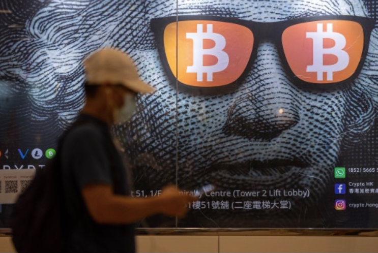 Một người đi qua bảng quảng cáo cho bitcoin ở Hong Kong ngày 25/9. (Ảnh: EPA)