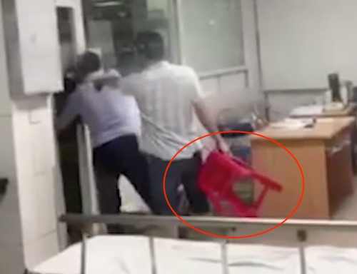 Ông Nguyễn Xuân Huân (người cầm ghế). Ảnh cắt từ video