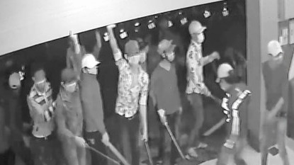 Các đối tượng dùng tay cản cửa cuốn, tay lăm lăm hung khí đe doạ nhân viên quán karaoke - Ảnh cắt từ clip