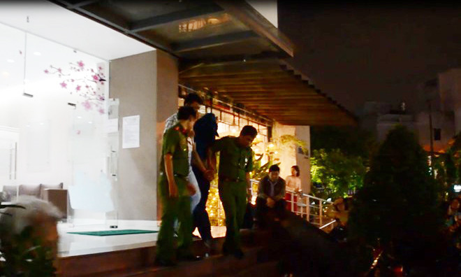 Nghi phạm bị cảnh sát trùm kín mặt, còng tay đưa về trụ sở. Ảnh: Zing