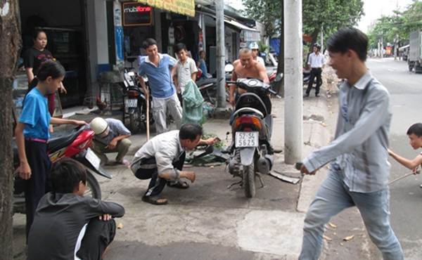 Nhiều người vây quanh xe máy để truy tìm con rắn.