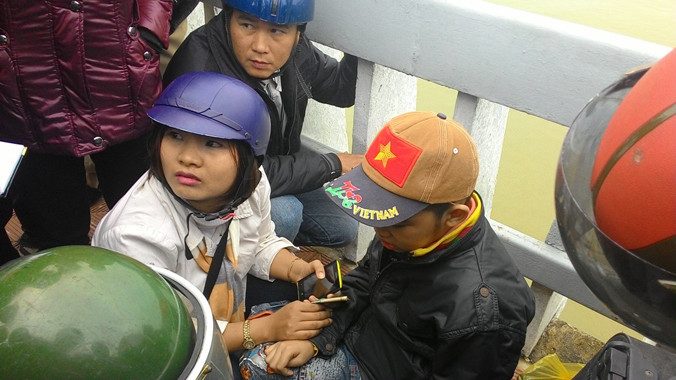 Nhiều người đi đường dừng lại hỏi thăm, chăm sóc cho S. (đội mũ vải) sau khi cháu bé lạc mất bố.