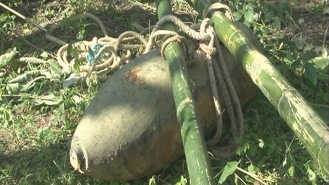 Quả bom được lực lượng chức năng và người dân trục vớt lên bờ.