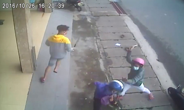 Các đối tượng xông vào chém 1 trong 2 thanh niên đi xe máy ngay trên lề đường. Hình cắt từ clip
