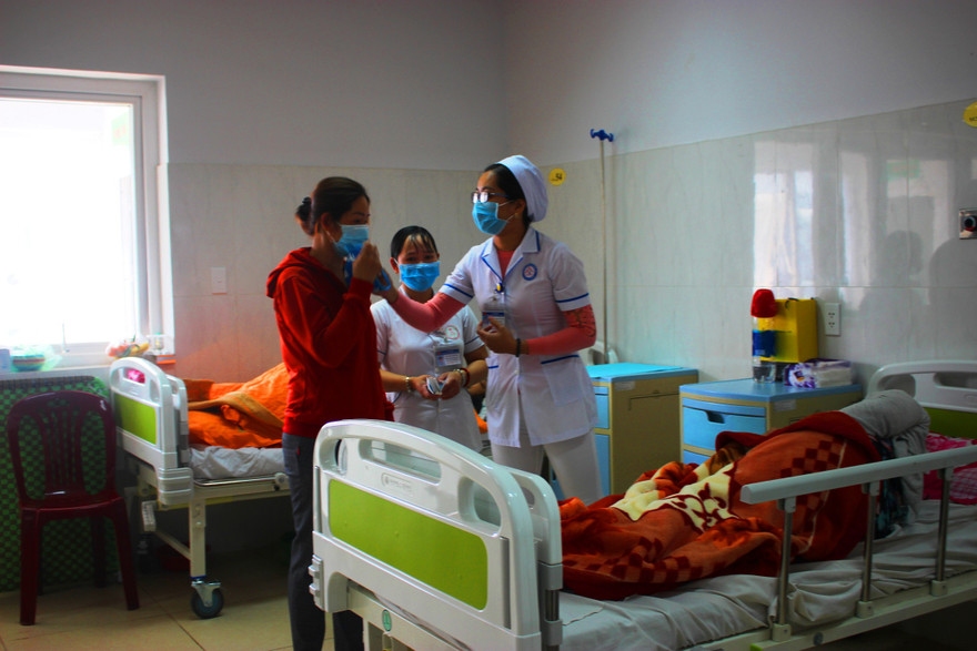 Cán bộ y tế hướng dẫn người dân đeo khẩu trang đúng cách