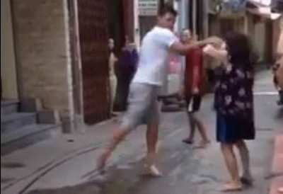 Hình ảnh người đàn ông còn rất trẻ dùng dép đánh mạnh vào mặt cụ bà. Ảnh cắt từ clip.