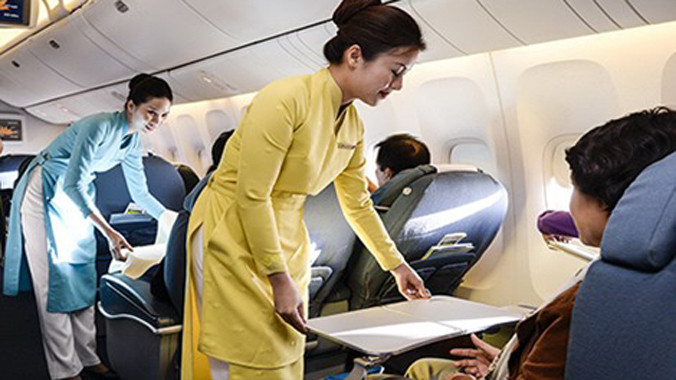 Tiếp viên VNA đang hướng dẫn du khách cách sử dụng bàn ăn. Ảnh: Quang Huy/Pháp Luật TPHCM.