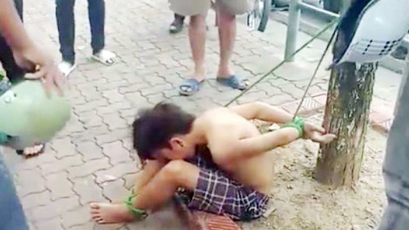 Hình ảnh thiếu niên 16 tuổi bị trói vào gốc cây