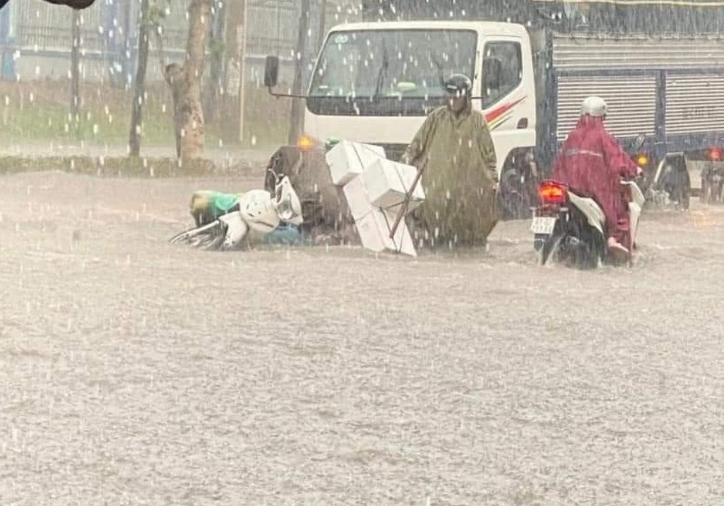 Một người chở hàng bằng xe máy bị ngã khi đi qua khu vực nước ngập sâu