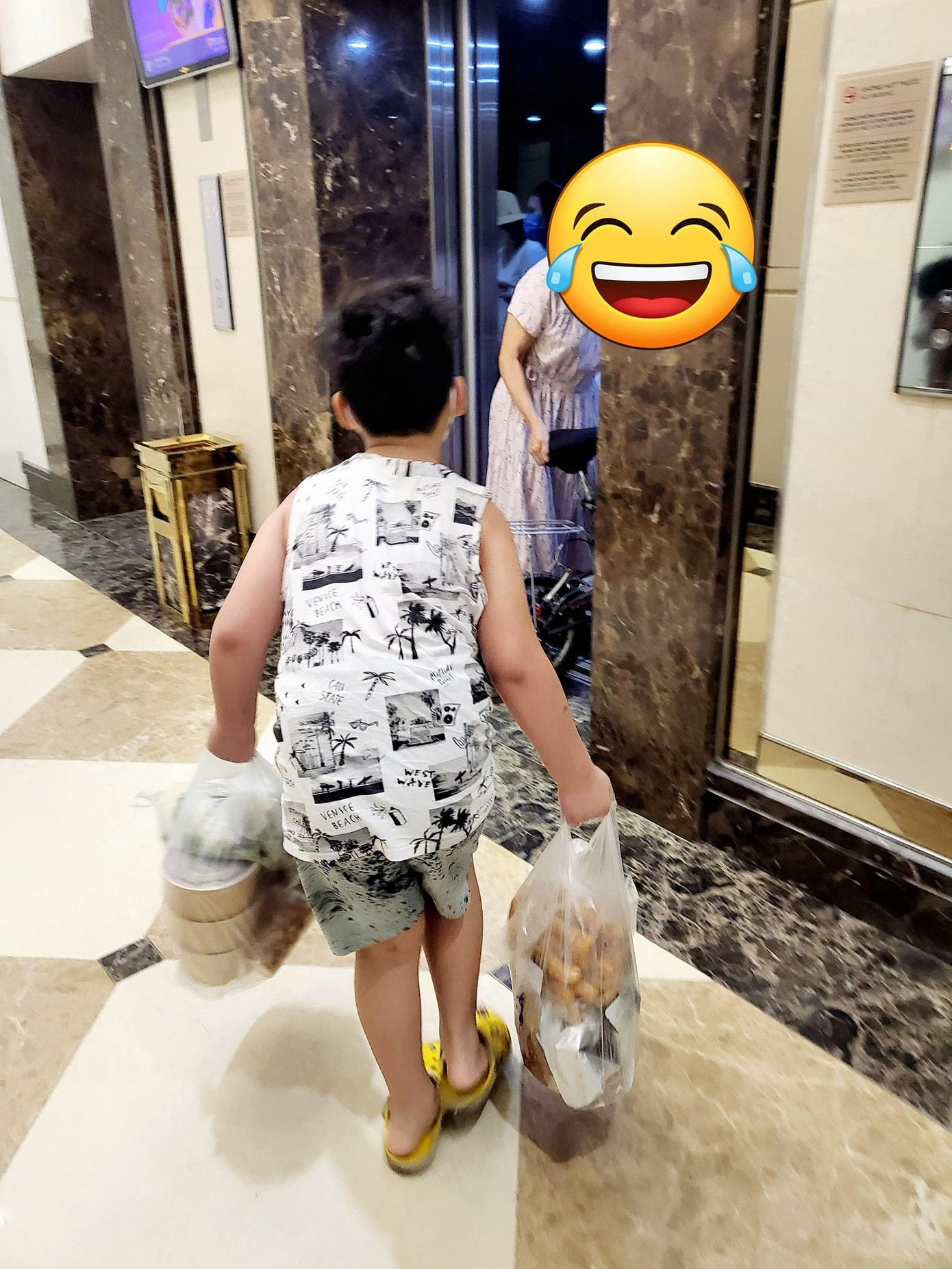 Vì túi đồ khá nặng nên cậu bé khá vất vả mới tới được thang máy. - Ảnh: FBNV. Vì túi đồ khá nặng nên cậu bé khá vất vả mới tới được thang máy. - Ảnh: FBNV.