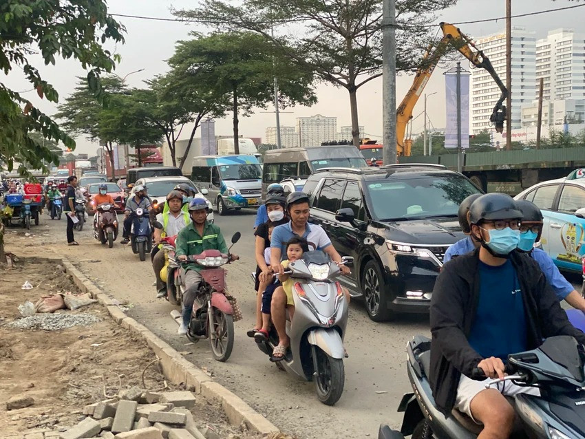 Người dân di chuyển chậm chạp qua đường Nguyễn Văn Linh khu vực công trình dự án hầm chui Nguyễn Văn Linh - Nguyễn Hữu Thọ, quận 7. Phía cần cẩu là hầm chui đang được xây dựng, vỉa hè trên đường này cũng bị xới tung lên ảnh hưởng người dân qua lại.