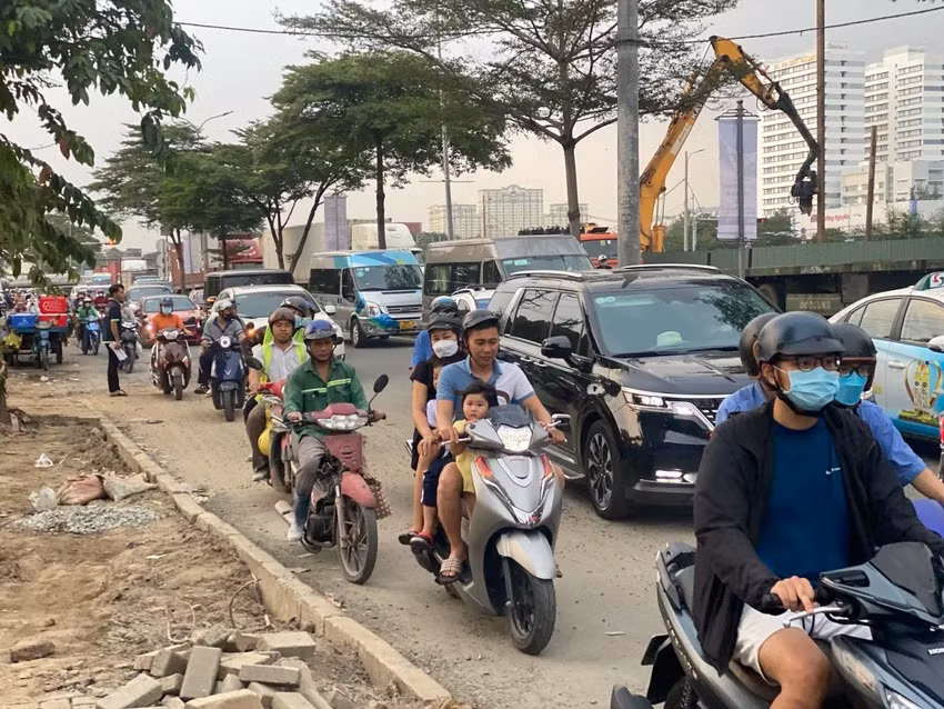 Người dân di chuyển chậm chạp qua đường Nguyễn Văn Linh khu vực công trình dự án hầm chui Nguyễn Văn Linh - Nguyễn Hữu Thọ, quận 7. Phía cần cẩu là hầm chui đang được xây dựng, vỉa hè trên đường này cũng bị xới tung lên ảnh hưởng người dân qua lại.
