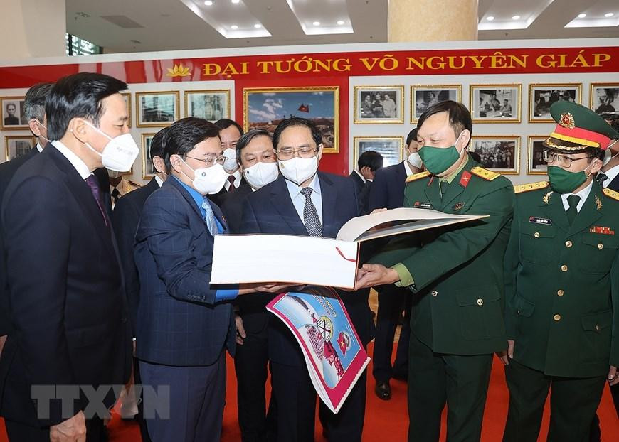 Thủ tướng Phạm Minh Chính và các đại biểu tham quan trưng bày ảnh và tư liệu, bài thi tìm hiểu về cuộc đời và sự nghiệp của Đại tướng Võ Nguyên Giáp. (Ảnh: Dương Giang/TTXVN)