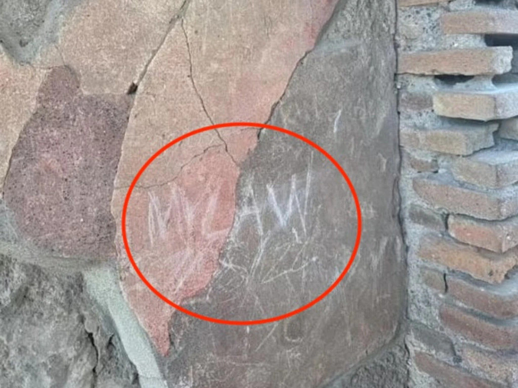 Nam du khách người Anh khắc tên viết tắt các thành viên trong gia đình lên tường của di tích cổ ở Pompeii. Ảnh: Jam Press.