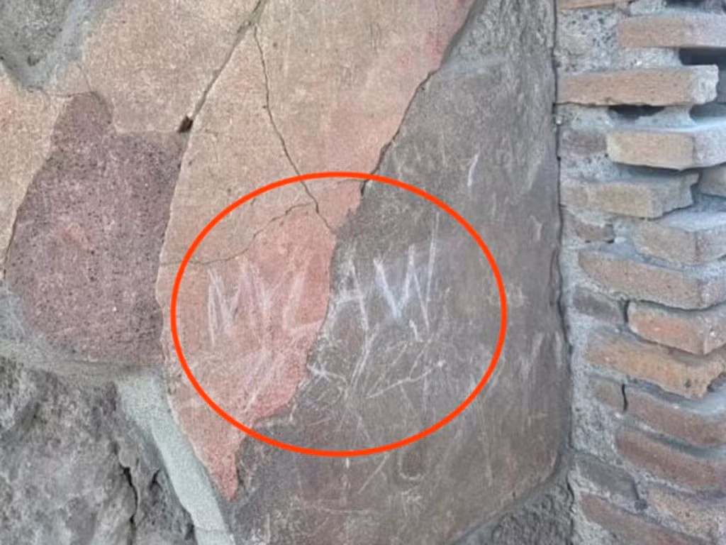 Nam du khách người Anh khắc tên viết tắt các thành viên trong gia đình lên tường của di tích cổ ở Pompeii. Ảnh: Jam Press.