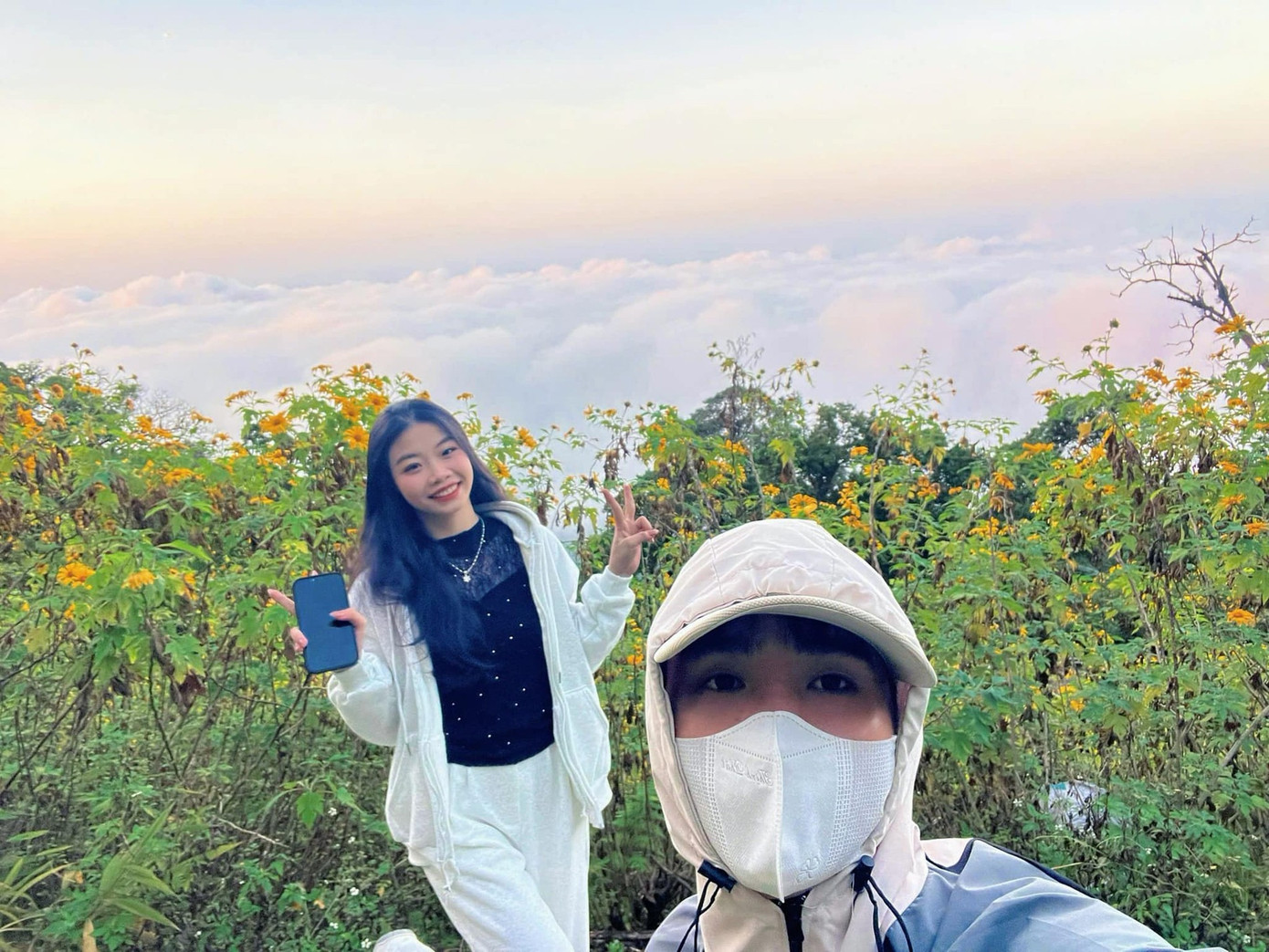 Vợ chồng chị Loan chụp hình "check-in" với biển mây và hoa dã quỳ ở VQG Ba Vì. Ảnh: Minh Loan.