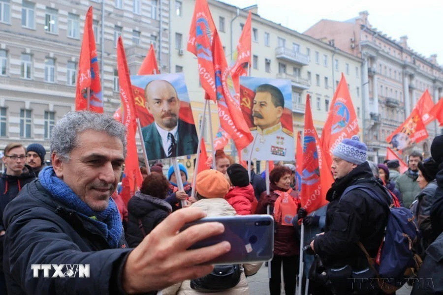 Người dân Moskva (Liên bang Nga) ghi lại hình ảnh đoàn người diễu hành qua các tuyến phố nhân kỷ niệm lần thứ 102 Cách mạng Tháng Mười vĩ đại (2019). (Ảnh: Trần Hiếu/TTXVN)