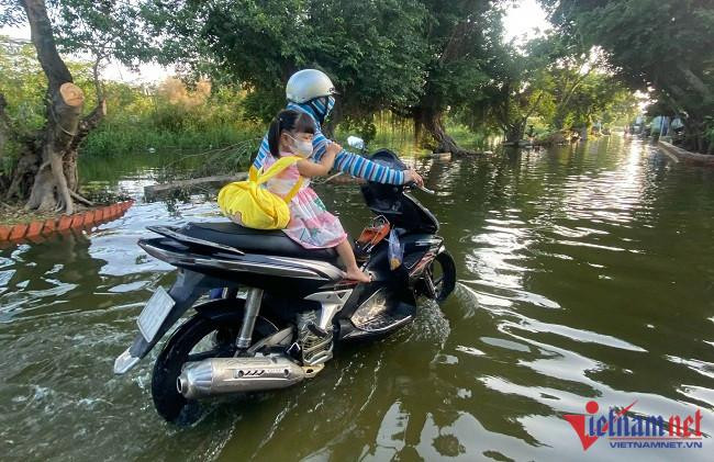 Phụ huynh chở con đi học, qua những đoạn nước sâu khá khó khăn Phụ huynh chở con đi học, qua những đoạn nước sâu khá khó khăn
