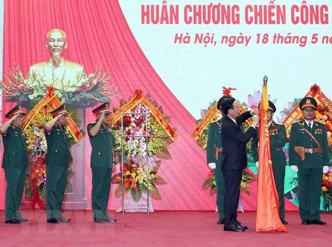 Chủ tịch nước Võ Văn Thưởng gắn Huân chương Chiến công hạng Nhất lên lá cờ truyền thống của Tổng Cục II, Bộ Quốc phòng. (Ảnh: Thống Nhất/TTXVN)