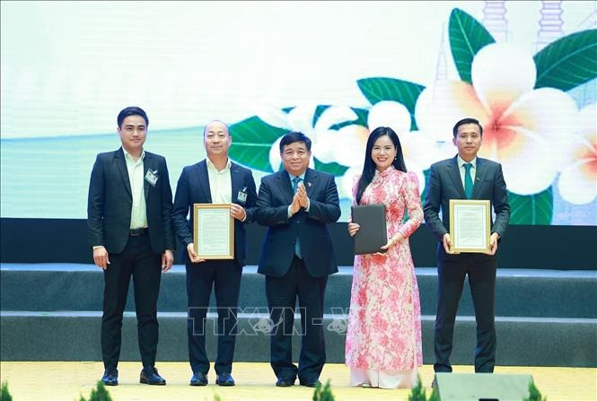 Bộ trưởng Bộ Kế hoạch và Đầu tư Nguyễn Chí Dũng trao chứng nhận đăng ký và thoả thuận đầu tư cho các doanh nghiệp Việt Nam có hợp tác với Lào. Ảnh: Dương Giang/TTXVN