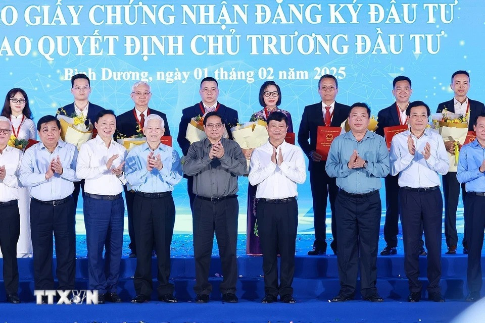 Thủ tướng Phạm Minh Chính và lãnh đạo tỉnh Bình Dương với các nhà đầu tư được trao giấy chứng nhận và quyết định chủ trương đầu tư. (Ảnh: Dương Giang/TTXVN)