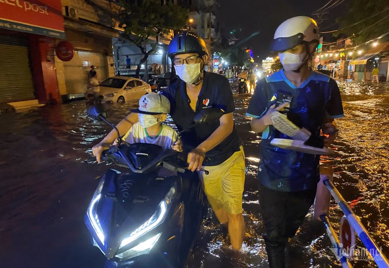 Người dân dẫn bộ xe chết máy qua 'rốn ngập' Nguyễn Văn Khối.