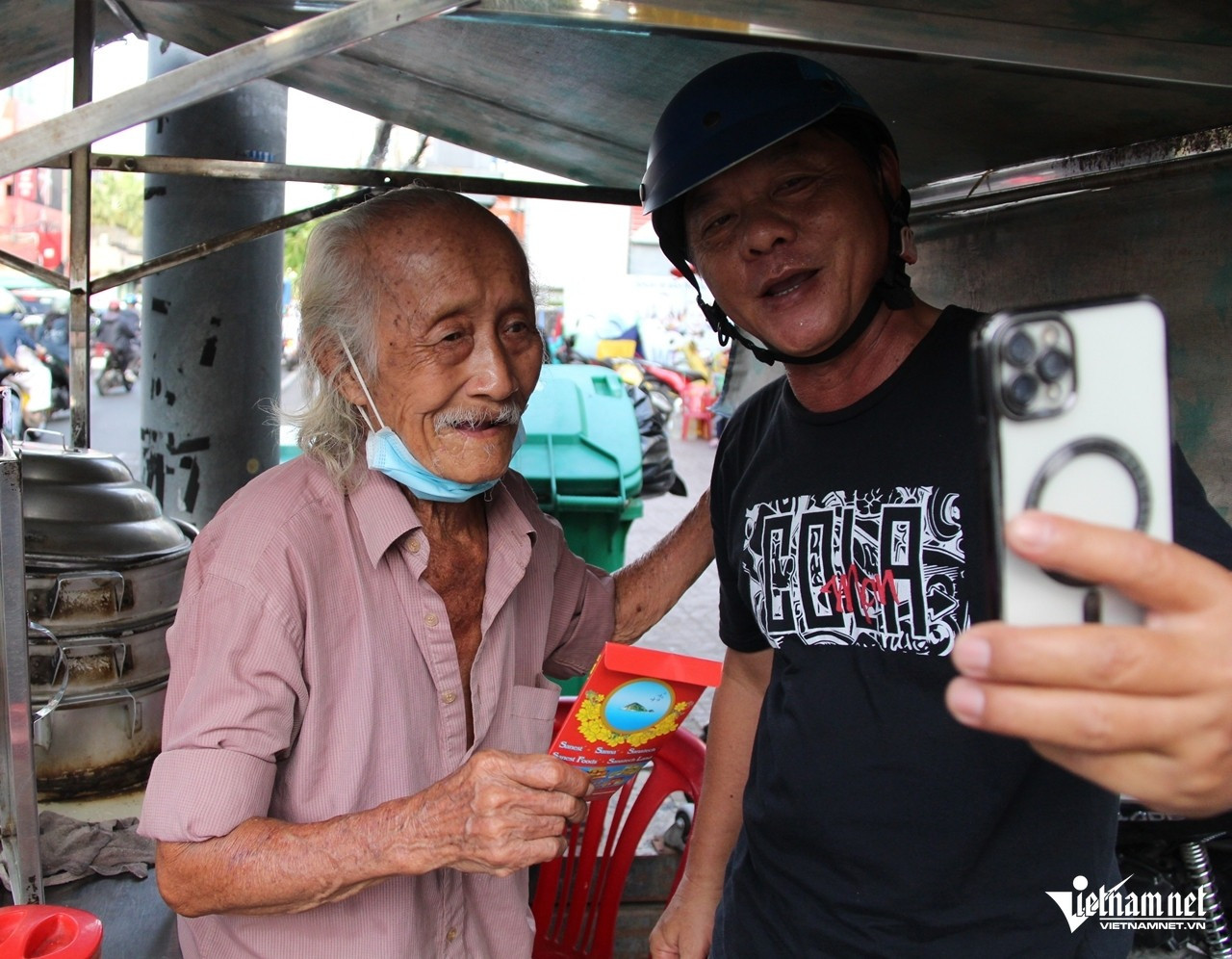 Người đàn ông đến thăm hỏi ông Thông rồi tặng bao lì xì đỏ như một cách chia sẻ, hỗ trợ ông trong cuộc mưu sinh. Ảnh: Hà Nguyễn Người đàn ông đến thăm hỏi ông Thông rồi tặng bao lì xì đỏ như một cách chia sẻ, hỗ trợ ông trong cuộc mưu sinh. Ảnh: Hà Nguyễn
