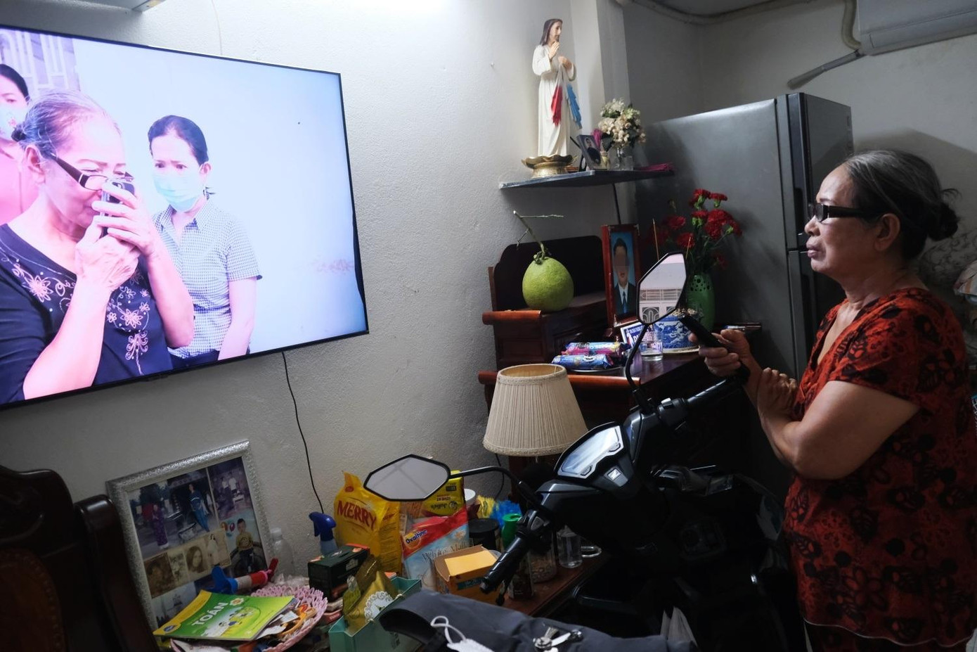 Cô Ngọt xem lại giây phút mình hôn trái tim của con đã đập trở lại sau ca ghép tạng, qua màn hình điện thoại (Ảnh: Hoàng Lê). Cô Ngọt xem lại giây phút mình hôn trái tim của con đã đập trở lại sau ca ghép tạng, qua màn hình điện thoại (Ảnh: Hoàng Lê).