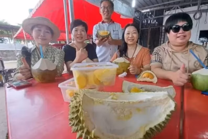 Khách du lịch Trung Quốc ăn sầu riêng tại một quầy trái cây ở Melaka. Ảnh: The Star. Khách du lịch Trung Quốc ăn sầu riêng tại một quầy trái cây ở Melaka. Ảnh: The Star.