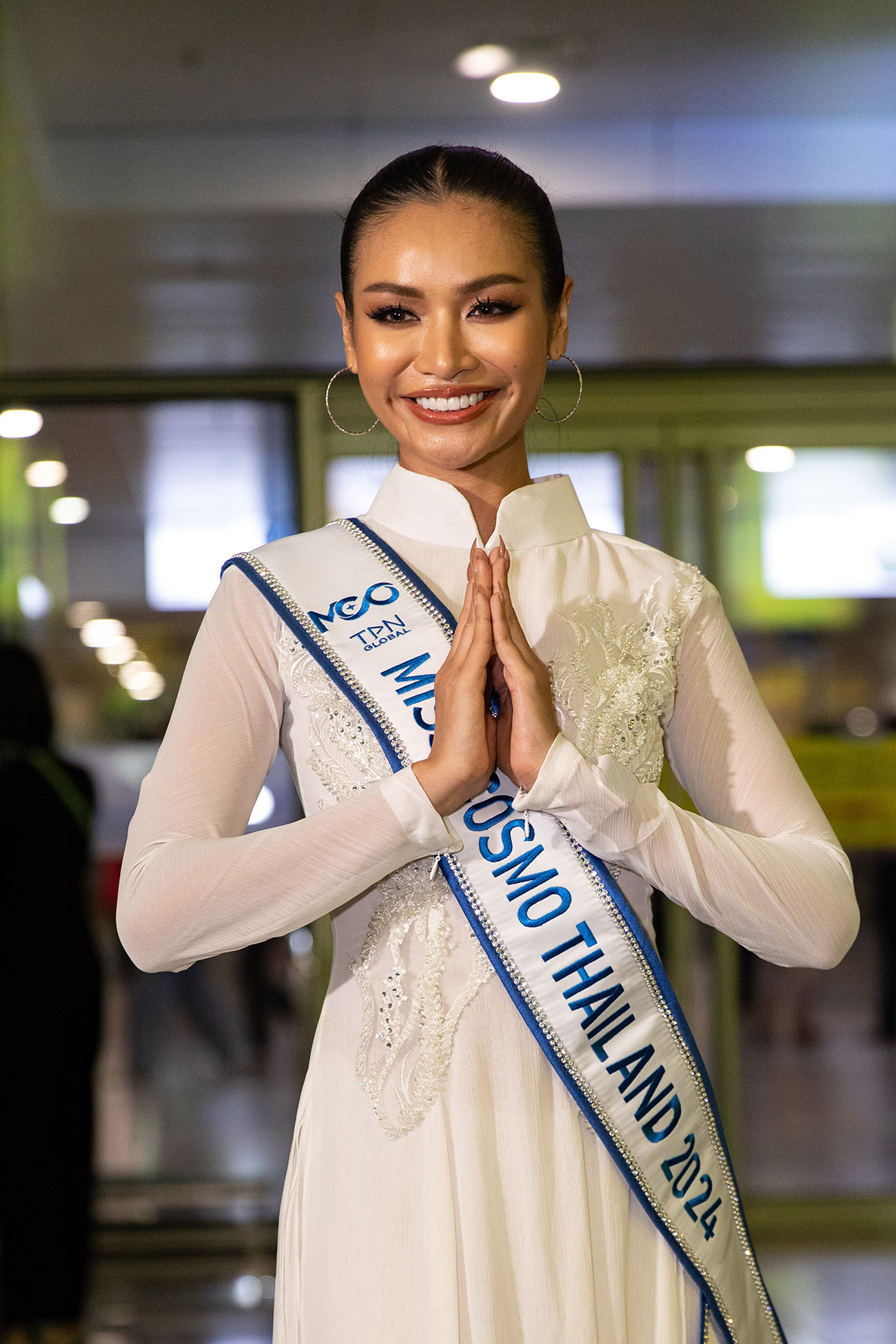 Đại diện Thái Lan gây chú ý khi xuất hiện ở sân bay trong bộ áo dài trắng nền nã. Cô được đánh giá là thí sinh tiềm năng của khu vực châu Á.