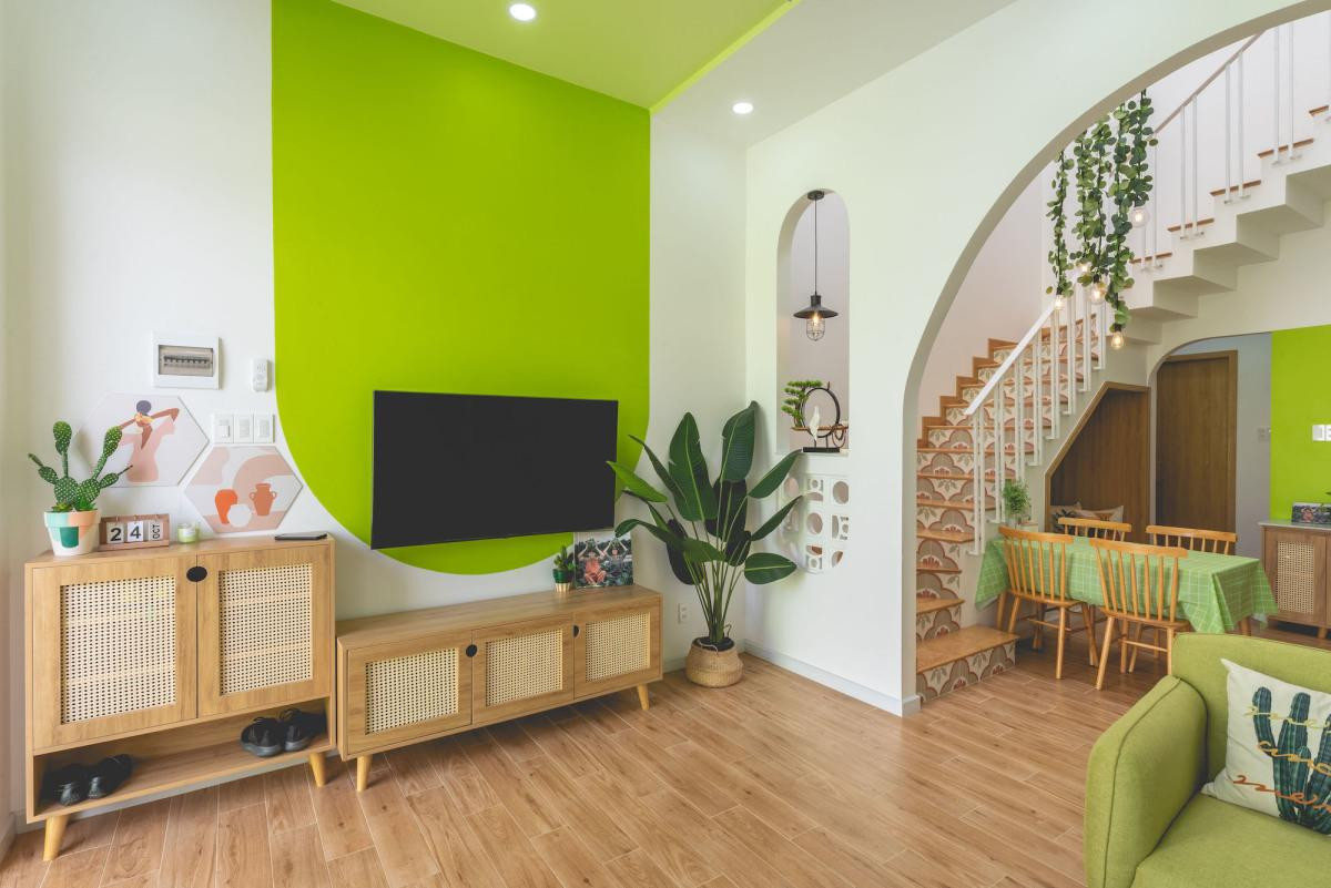 Từ sân vào là phòng khách ở tầng trệt. Phòng khách kết hợp giữa tông xanh lá cây và trắng, có bệ ngồi ở cửa sổ lớn.