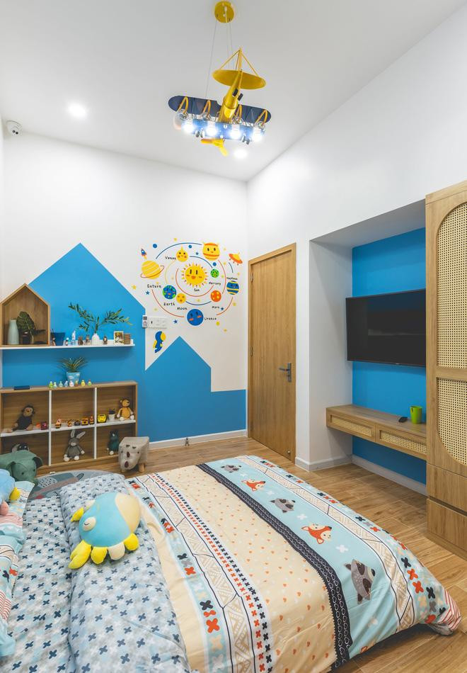 Phòng ngủ của con lấy tông màu xanh dương làm chủ đạo để gợi trí sáng tạo. Đồ chơi được bày biện cả trên bóng đèn và các kệ tủ.