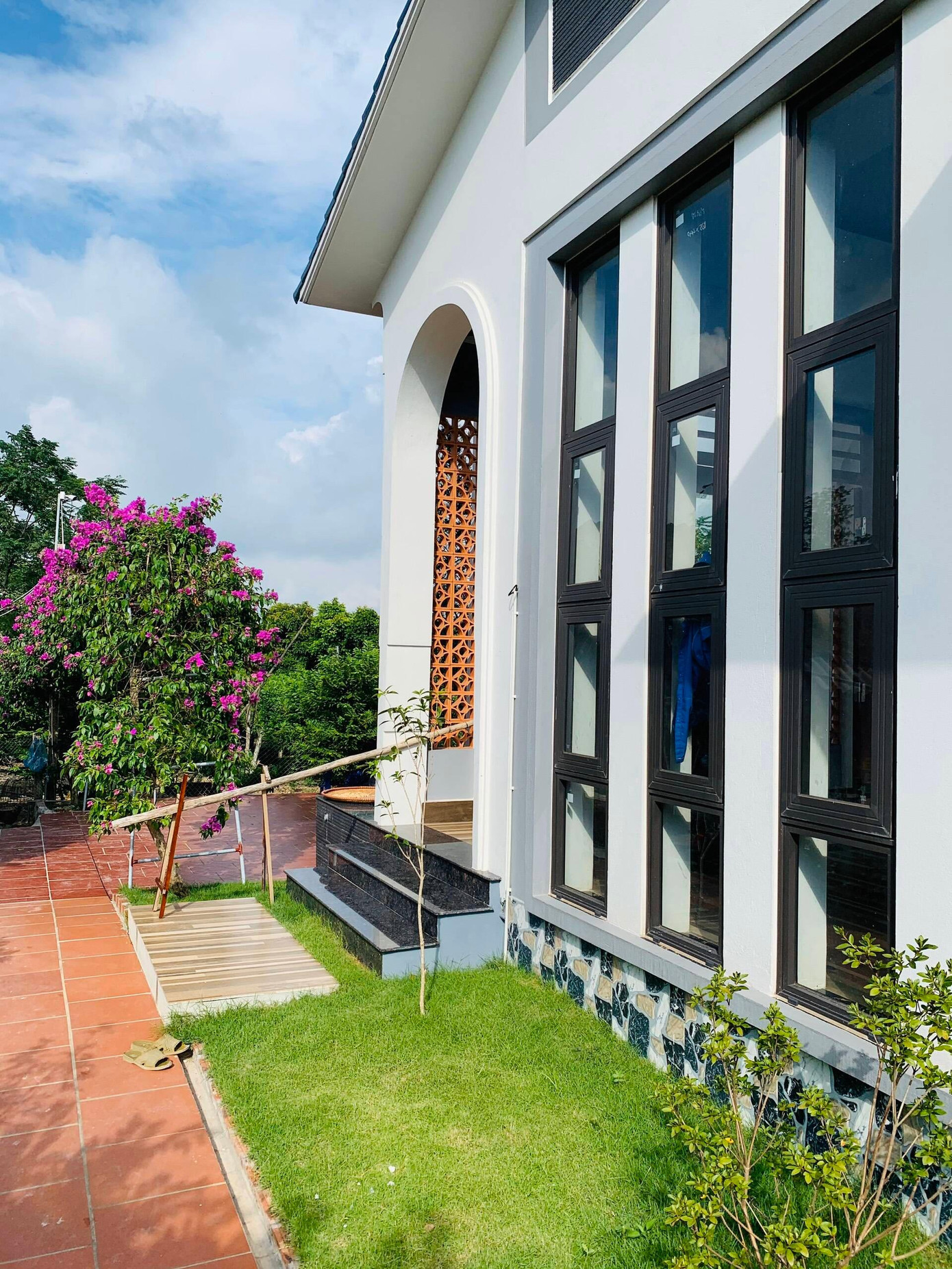 Ngôi biệt thự sau khi hoàn thành có màu sắc trung tính, kiến trúc hiện đại nổi bật giữa khu vườn rộng rãi và xanh mát.