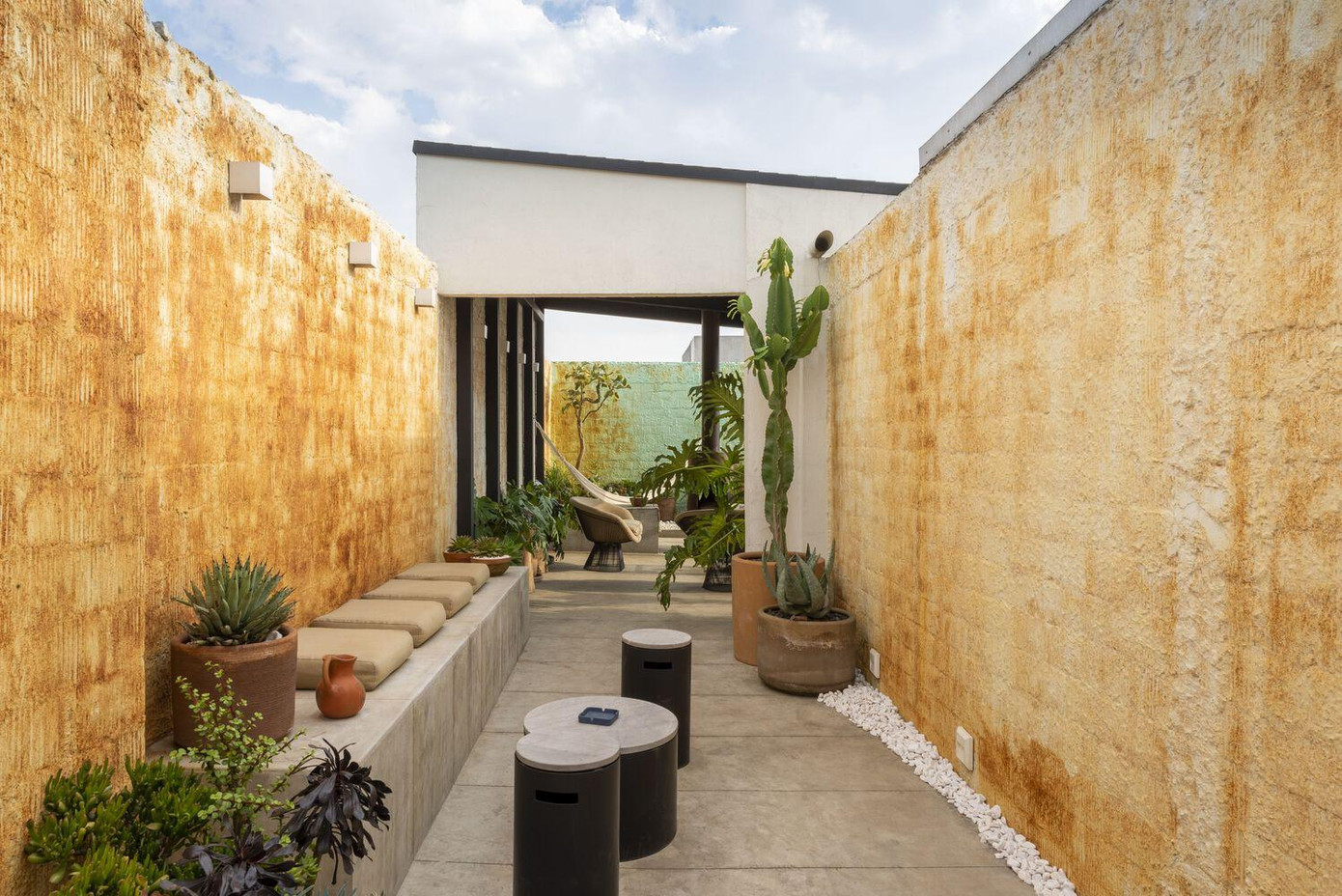 Có thể thấy, kiến trúc sư đã khéo léo tận dụng các bức tường lớn sẵn có để tạo ra một hành lang cây xanh có bày biện ghế ngồi.