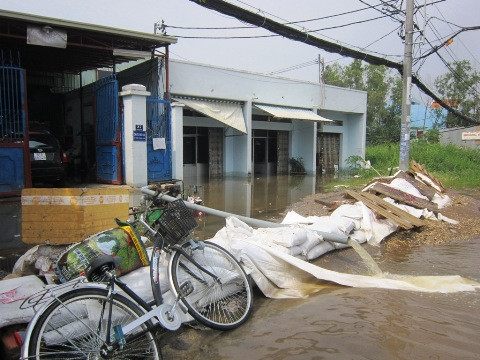 Nhà dân hai bên đường mặc dù đã được đắp bao cát gia cố nhưng nước vẫn tràn vào khiến đời sống bị đảo lộn
