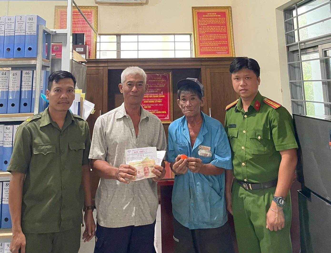 Ông Cà (áo trắng) trả lại tài sản cho ông Thành (áo xanh) tại Công an xã Phước An Ông Cà (áo trắng) trả lại tài sản cho ông Thành (áo xanh) tại Công an xã Phước An