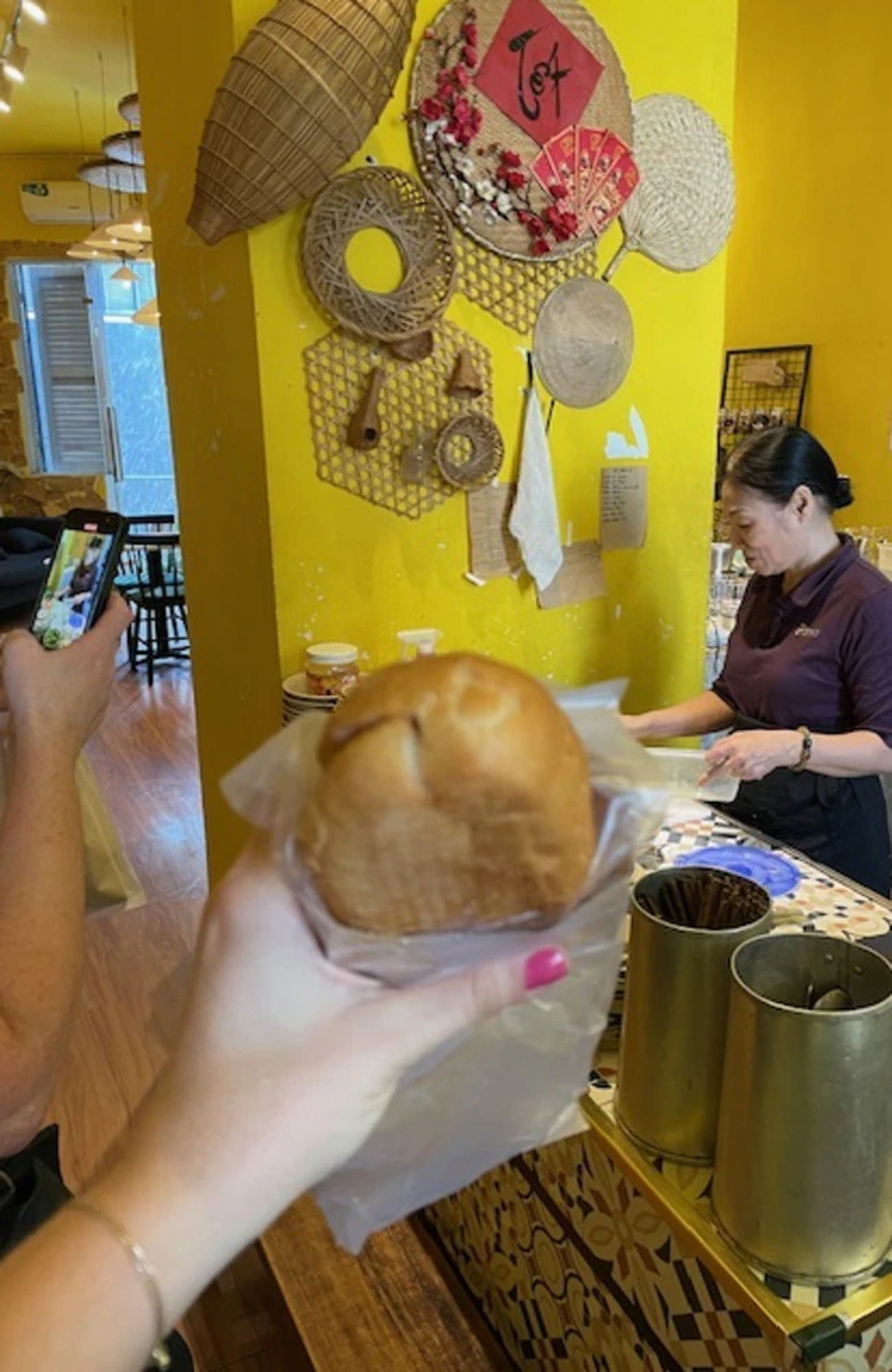 Cô gái mua suất bánh mì kẹp thịt tại một cửa tiệm ở chung cư (Ảnh: News).