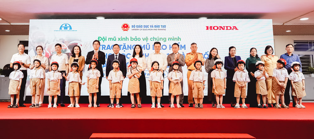 Các đại biểu trao tặng mũ bảo hiểm cho các em học sinh lớp 1, Trường Tiểu học Vạn Bảo (phường Vạn Phúc, quận Hà Đông)