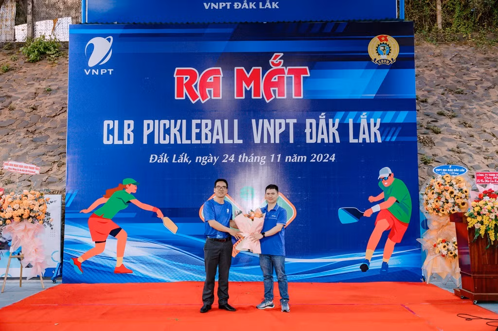 Chủ nhiệm CLB Pickleball VNPT Đắk Lắk Bùi Văn Phúc (phải) nhận hoa chúc mừng từ Phó Giám đốc Nguyễn Văn Thản