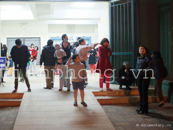 Nhiều gia đình ở chung cư thuộc khu đô thị Bắc Linh Đàm kéo xuống tầng 1 của toà nhà. Nhiều người tỏ ra lo lắng và liên tục phải trả lời điện thoại hỏi thăm của người thân. Ảnh: Thành Long.