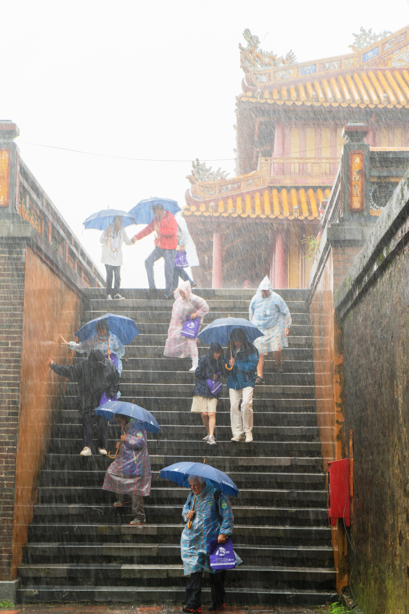 Đoàn khách tham quan di tích lầu Ngũ Phụng - Đại nội Huế dưới cơn mưa lớn (Ảnh: Bảo Minh).