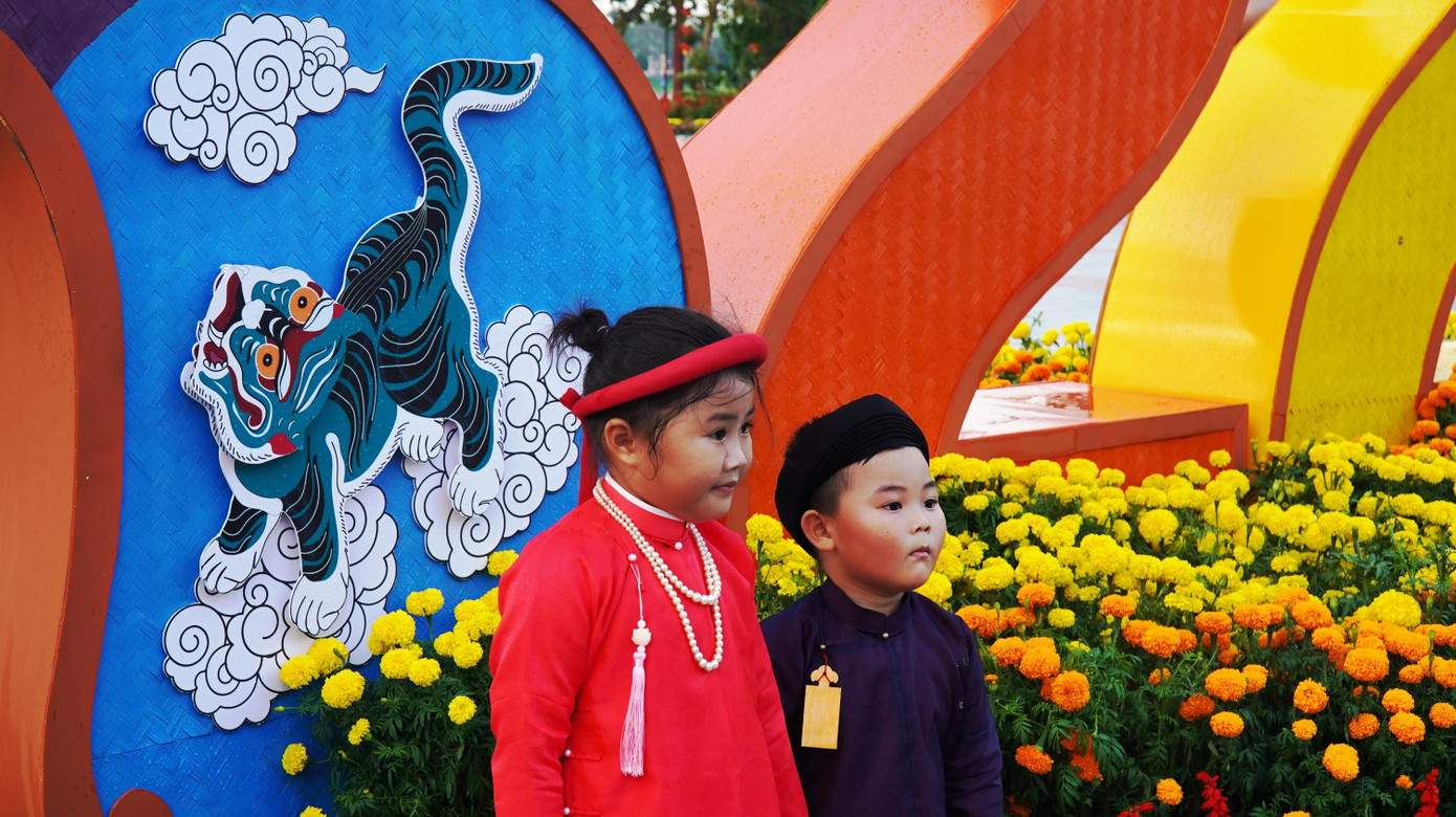 Trẻ em Huế trong áo dài ngũ thân chụp hình bên cụm linh vật ngũ hổ.