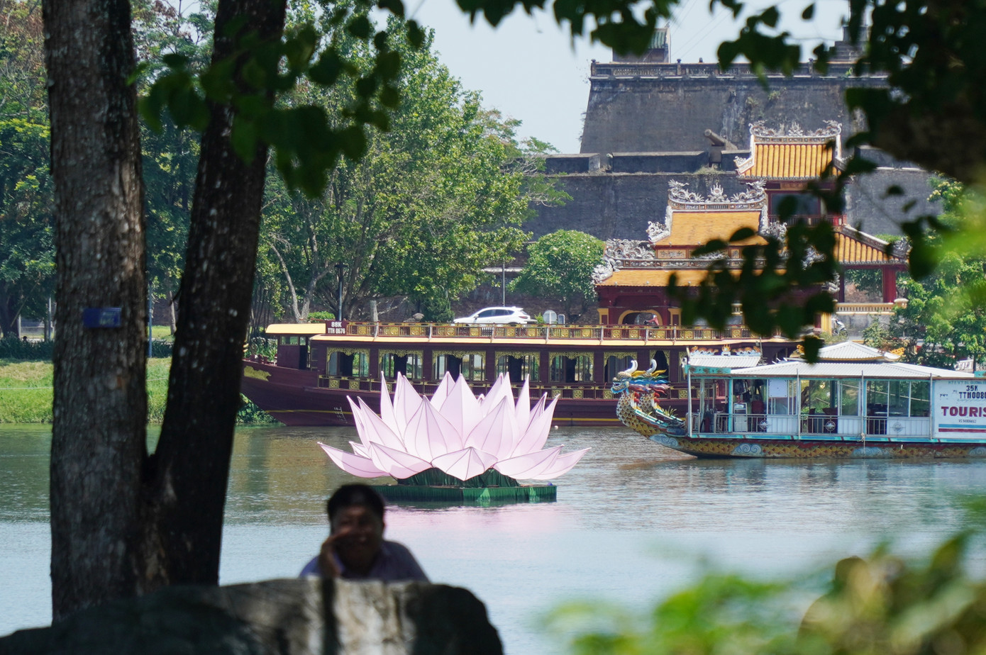 Một đóa sen hồng nổi bật trên sông Hương hòa trong khung cảnh cổ kính của di tích thành quách, Kỳ đài Phu Vân Lâu xứ Huế.