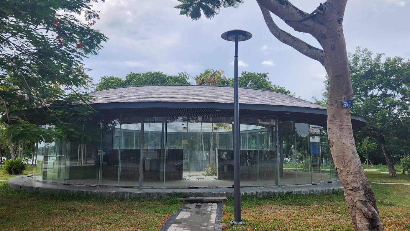 Khu nhà vệ sinh tại công viên Kim Long trong giai đoạn hoàn thiện, với cấu trúc hiện đại, công trình có dạng hình tròn, mái ngói sậm màu, xung quanh được gắn kính trong suốt.