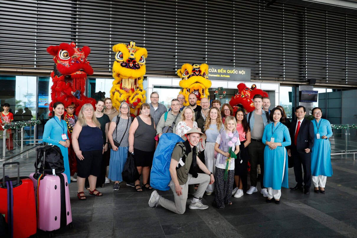 Du khách quốc tế hào hứng chụp hình lưu niệm với người làm ngành du lịch Huế khi vừa xuống máy bay tại sân bay Phú Bài (Huế). (Ảnh: SDL)