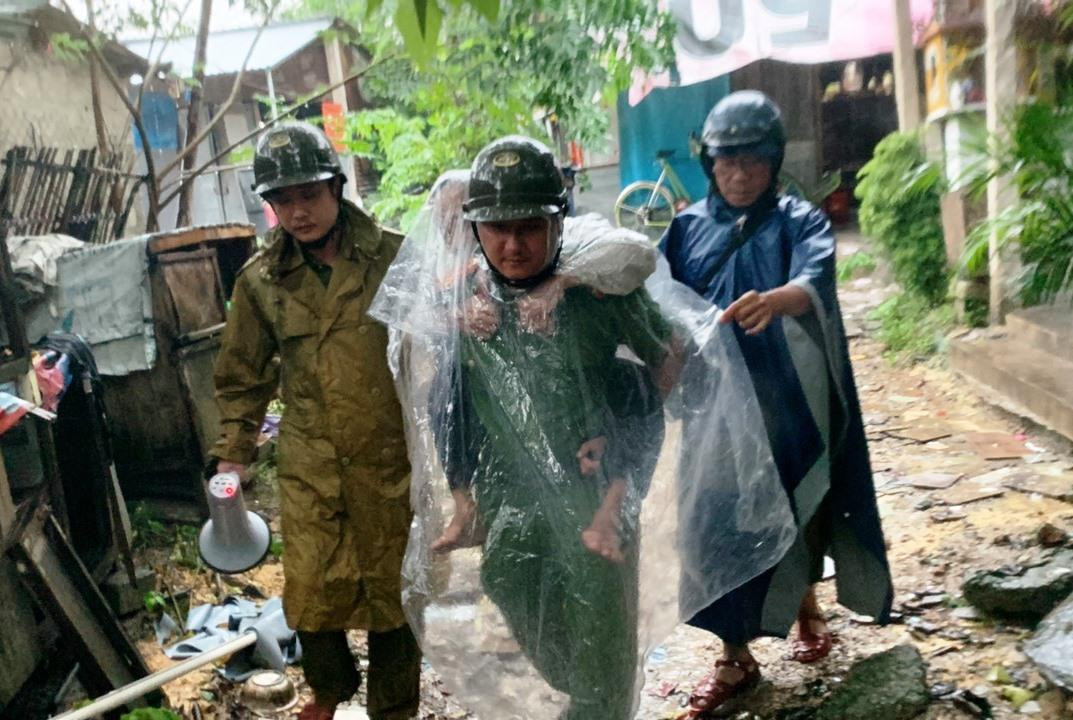 Tại xã ven biển Lộc Vĩnh (huyện Phú Lộc) - một trong những nơi gần tâm bão nhất của tỉnh TT-Huế, hàng chục hộ dân vùng nguy hiểm được di dời đến Trường Tiểu học Lộc Vĩnh. Chính quyền địa phương đã bố trí nơi ăn, nghỉ an toàn cho bà con trong thời gian xảy ra mưa bão. Trong ảnh: Lực lượng công an tại TT-Huế đội mưa đưa người già, khuyết tật đi trú tránh bão.